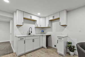 Kitchen with white cabinetry, light wood-type flooring, recessed lighting, and light colored countertops