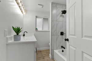 Full bathroom featuring vanity, washtub / shower combination, and light wood-type flooring