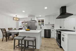 Kitchen with gas stove, a breakfast bar, exhaust hood, stainless steel refrigerator with ice dispenser, and white cabinetry