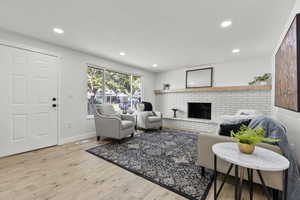 Living room featuring light wood finished floors, a fireplace, and recessed lighting