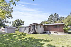 Rear view of house with brick siding, a chimney, and a lawn