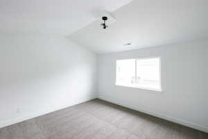 Spare room with vaulted ceiling and carpet floors