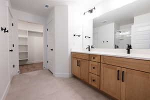 Full bathroom featuring double vanity, a spacious closet, a stall shower, and light tile patterned floors