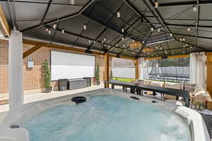 View of patio / terrace with a hot tub and a trampoline