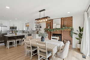 Dining room featuring a brick fireplace, light wood finished floors, and recessed lighting