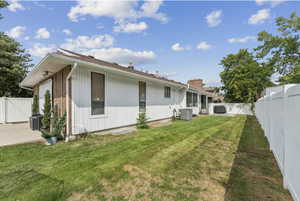 Back of house featuring a fenced backyard, a gate, a chimney, and brick siding