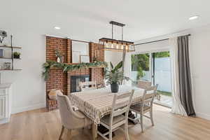 Dining room with light wood-style floors, recessed lighting, and a fireplace