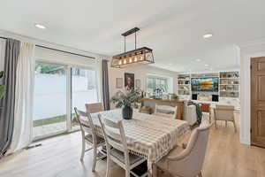 Dining room with recessed lighting, light wood-type flooring, built in features, and ornamental molding