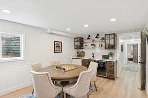 Dining area featuring recessed lighting, light wood-type flooring, beverage cooler, and wet bar