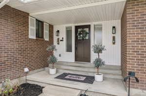View of exterior entry with a porch and brick siding