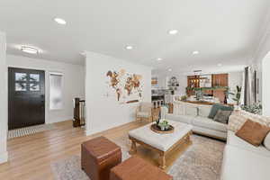 Living room with light wood-style floors, recessed lighting, and crown molding