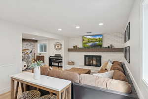 Living area featuring a brick fireplace, light wood-style floors, and recessed lighting