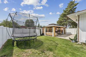 Fenced backyard with a gazebo, a patio area, and a trampoline