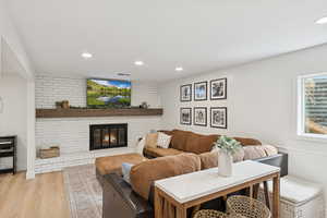 Living area with recessed lighting, light wood-style floors, and a brick fireplace