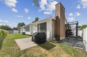 Rear view of property with a fenced backyard, a patio, and a chimney