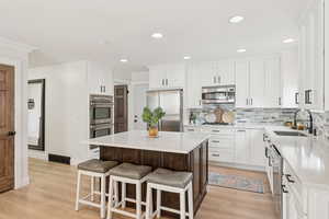 Kitchen with dark brown cabinets, stainless steel appliances, a kitchen breakfast bar, tasteful backsplash, and a center island