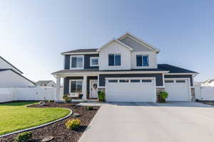 Craftsman-style home featuring a gate, a porch, concrete driveway, board and batten siding, and stone siding