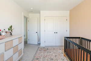 Bedroom with a nursery area, a closet, and light carpet