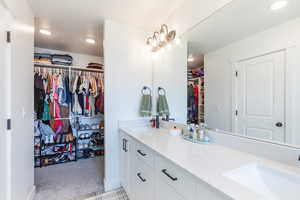 Bathroom featuring a walk in closet, double vanity, and recessed lighting