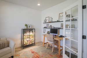 Office with light wood-style flooring and recessed lighting