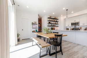 Dining space with light wood finished floors and recessed lighting