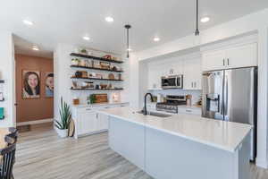 Kitchen with tasteful backsplash, white cabinets, hanging light fixtures, and recessed lighting