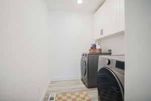 Laundry area featuring light wood finished floors, washer and dryer, cabinet space, and recessed lighting