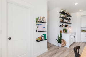 Bar featuring white cabinetry, light wood-type flooring, open shelves, tasteful backsplash, and recessed lighting