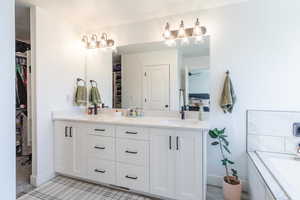 Bathroom featuring a spacious closet, double vanity, a bath, ensuite bathroom, and ceiling fan