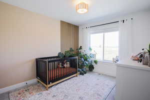 Carpeted bedroom featuring baseboards and a nursery area
