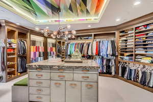 Walk in closet featuring a chandelier, a tray ceiling, and light carpet