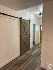 Hall with a barn door and dark wood-style flooring