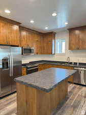 Kitchen with dark countertops, stainless steel appliances, brown cabinetry, a center island, and a textured ceiling