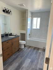 Full bathroom with dark wood finished floors, bathtub / shower combination, a textured ceiling, and vanity