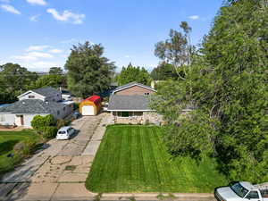 View of green lawn with driveway and a garage
