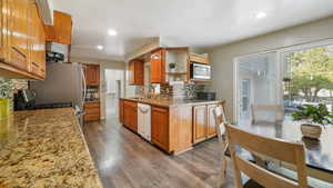 Kitchen featuring light stone counters, dark wood-type flooring, backsplash, open shelves, and brown cabinets