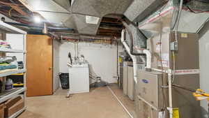 Unfinished below grade area featuring washer / dryer and strapped water heater