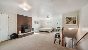 Carpeted bedroom featuring a fireplace and a textured ceiling