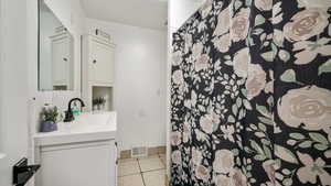 Full bath featuring light tile patterned floors, vanity, and a shower with shower curtain