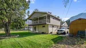 Back of house with a mountain view, brick siding, an outbuilding, and a balcony