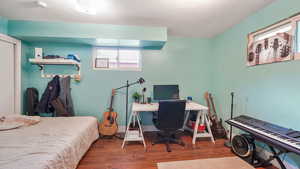 Bedroom featuring wood finished floors, a textured ceiling, and a desk