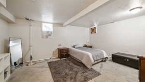 Bedroom featuring a textured ceiling and unfinished concrete floors