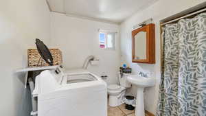 Full bath with independent washer and dryer, light tile patterned floors, a shower with curtain, and crown molding
