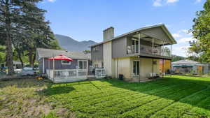 Rear view of house featuring a chimney, a balcony, a deck with mountain view, and brick siding