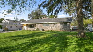 View of front of property featuring stone siding, a front lawn, a chimney, and covered porch