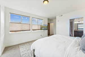 Carpeted bedroom featuring baseboards and ensuite bathroom