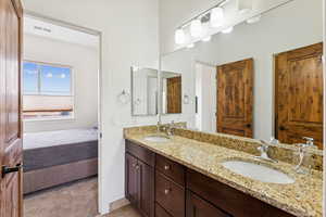 Ensuite bathroom featuring double vanity and light tile patterned floors