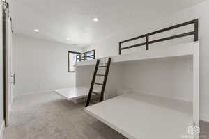 Unfurnished bedroom featuring light carpet, a textured ceiling, and recessed lighting