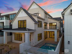 Rear view of house with a balcony, a standing seam roof, a metal roof, stucco siding, and a patio area