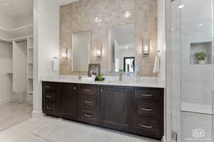 Full bathroom featuring tile walls, double vanity, light tile patterned flooring, a closet, and tiled shower